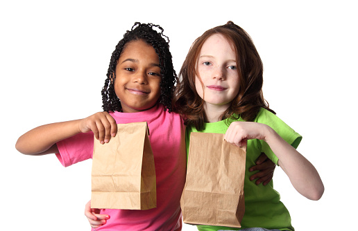 Two little girls comparing their bag lunches
