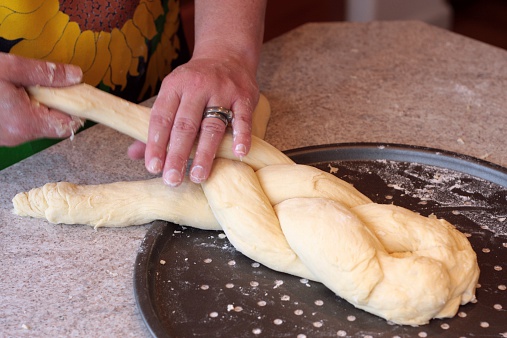 A woman braiding challah (a Jewish braided bread).