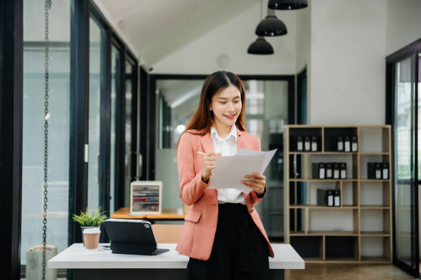 istock Young beautiful woman typing on tablet and laptop while sitting at the working white table modern office 1746293849