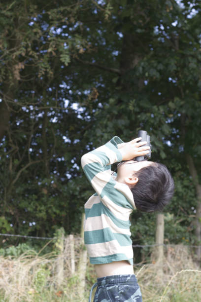 istock Child boy using magnifying glass and binoculars for experiment wildlife bird insects out door in the woodland meadow field. 1746298031