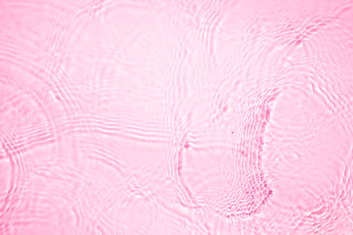 Close-up, directly above on pink transparent waving water texture.