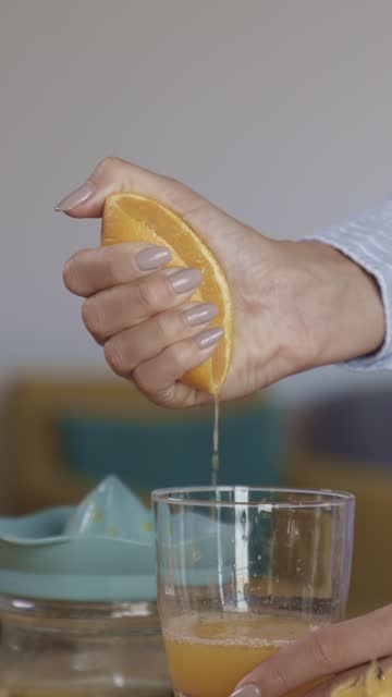 Woman squeezing fresh orange juice into a drinking glass