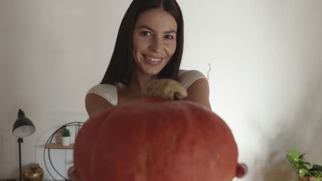 Woman smiling at camera and giving you a pumpkin