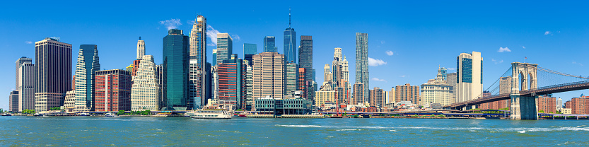 Stitched Panorama of Manhattan Lower East Side Financial District, Brooklyn Bridge, World Trade Center, Blue Sky with Clouds and Water of East River, New York, USA. Canon EOS 6D (Full Frame censor) DSLR and Canon EF 24-105mm f/4L lens. 4:1 Image Aspect Ratio.