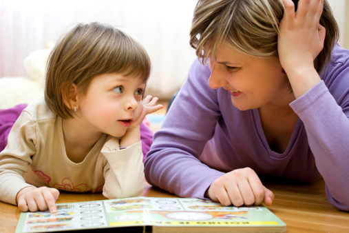Mother and child having fun while teaching and playing together. They reading picture book.