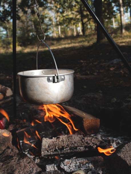 Close-up of a metal cooking pot on an open flame burning, emitting smoke and heat A close-up of a metal cooking pot on an open flame burning, emitting smoke and heat braising pan stock pictures, royalty-free photos & images