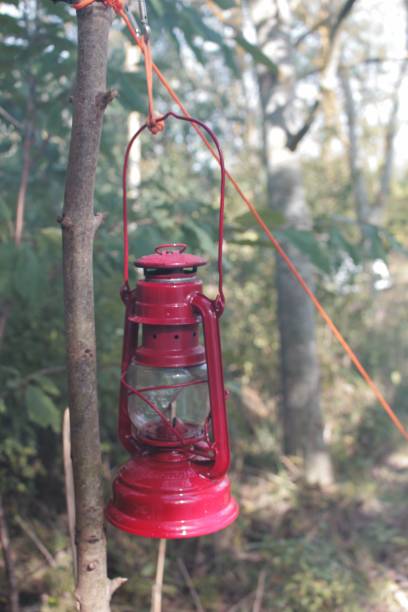 istock Outdoor red kerosene lantern hanging from a tree branch with a rope attached to the handle 1746320930