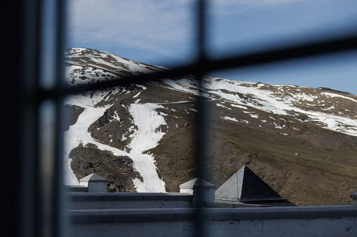 View of the mountain and snow tracks through the window of an apartment or hotel