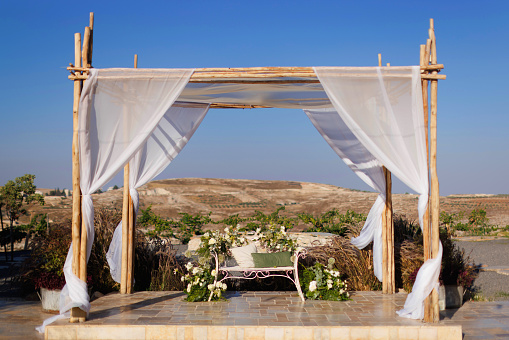 A beautiful Jewish wedding chuppah decorated with bright flowers and white curtains. Mountain View