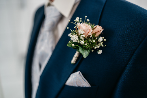 groom in blue suit wears a pocket square and a butonniere with rose flowers