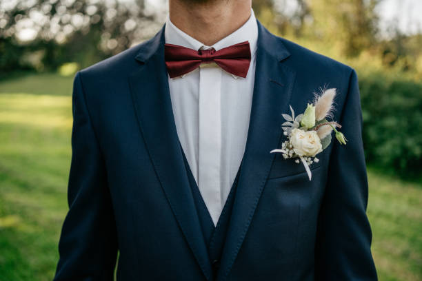 el novio con traje azul lleva un pañuelo de bolsillo y un butonniere - boutonniere fotografías e imágenes de stock