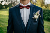 groom in blue suit wears a pocket square and a butonniere