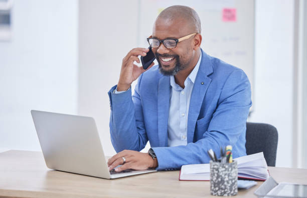istock Black man, laptop and phone call communication in office for web design, online conversation or smile reading tech email. African businessman, happy planning strategy and talking on smartphone call 1746333438