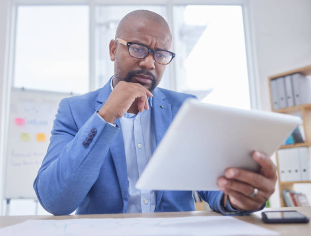 istock Black man, tablet and serious thinking face in office for web design, online communication or reading tech email in office. African businessman, digital search or boss planning strategy on device 1746333850