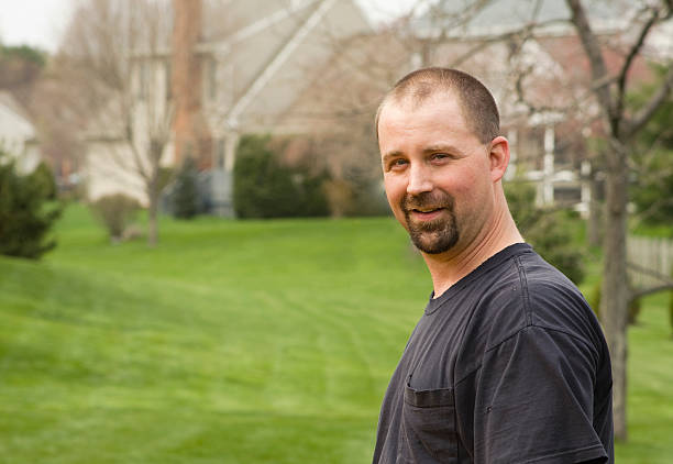 Man in the Yard "Man stands with the neighborhood yards and houses behind him. Smiling and content, he looks at the camera." crew cut stock pictures, royalty-free photos & images