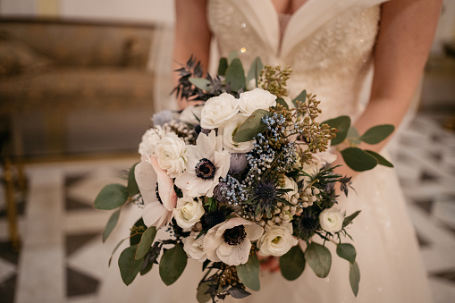 the bride holds a wedding bouquet with white flowers in her hand during a winter wedding