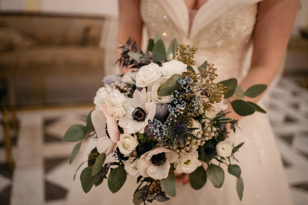 the bride holds a wedding bouquet with white flowers in her hand the bride holds a wedding bouquet with white flowers in her hand during a winter wedding bride holding bouquet stock pictures, royalty-free photos & images