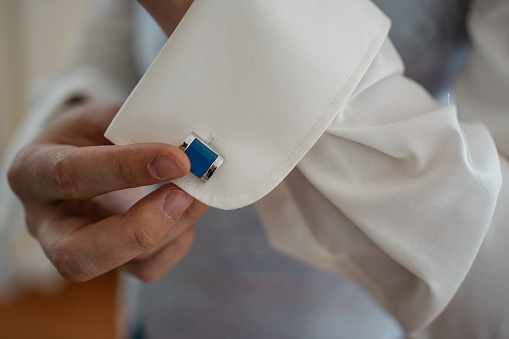 businessman is buttoning up his cufflink at a wedding