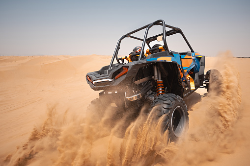 Rear view of dirt bike race riding fast on off-road dirt track.