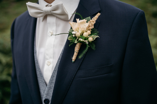 groom with bow tie and lapel flower, wearing a blue suit and vest