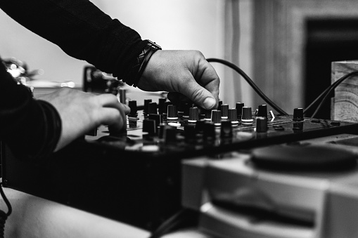 Black and White photo of a dj operating the mixer at a party