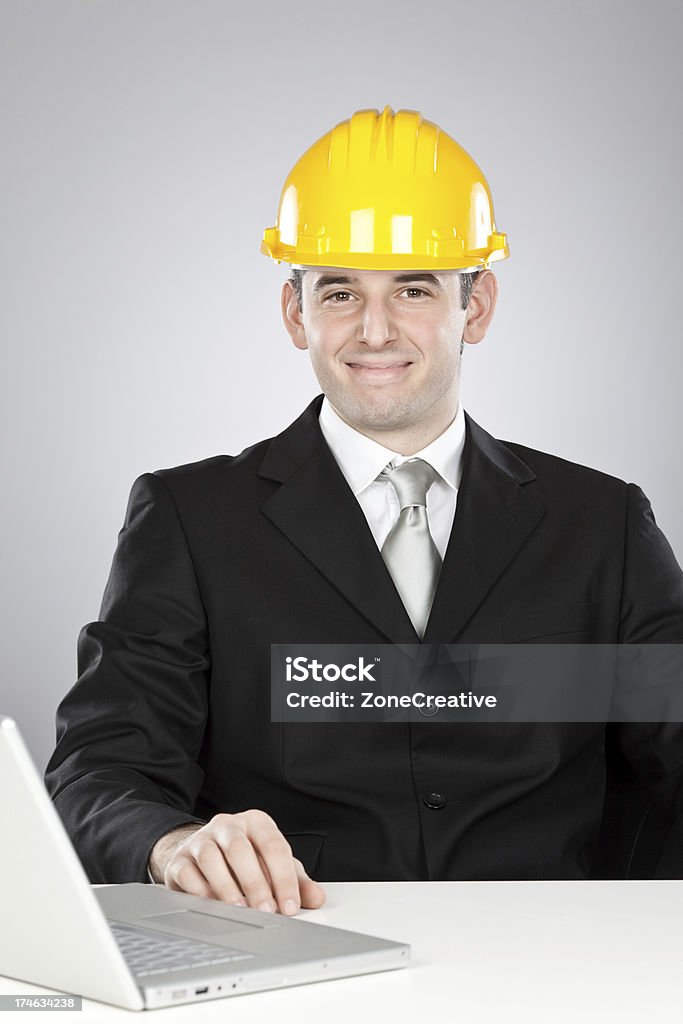 Bellissimo ingegnere con casco giallo e laptop - Foto stock royalty-free di Abbigliamento elegante