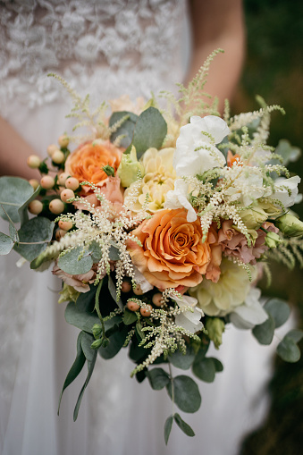 bride holding her wedding flowers with rose colored roses