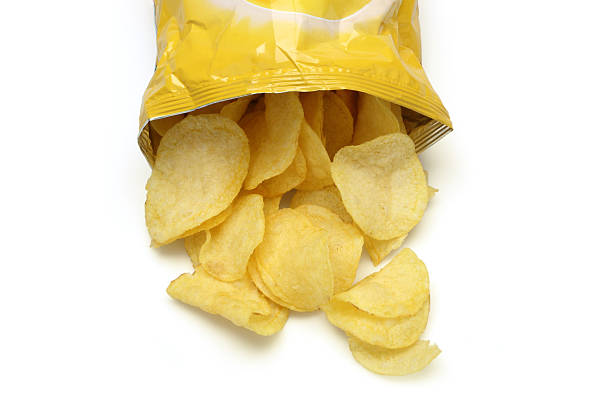 Chips spilling out of an open bag Bag of golden chips isolated on a white background. crisps stock pictures, royalty-free photos & images