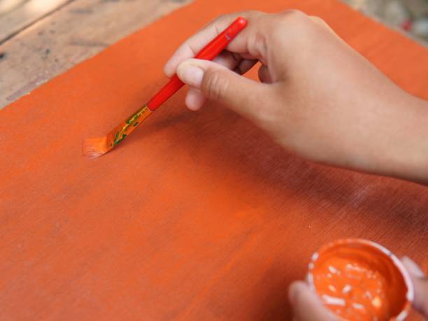 istock someone's hand is painting orange on a board 1746347302