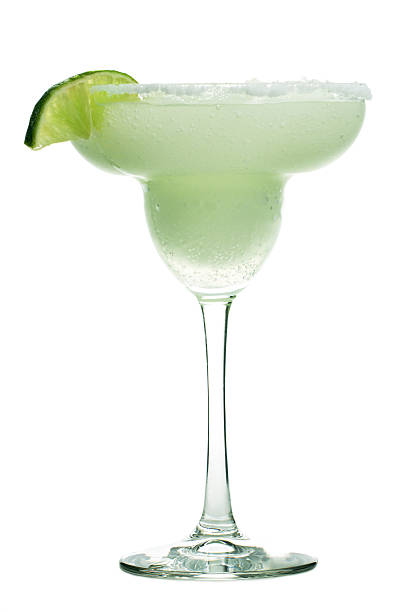 Margarita Cocktail Drink in Glass, Frozen Alcohol with Lime, Salt A blended frozen Margarita cocktail drink. The alcoholic beverage is a blended drink of tequilla, triple sec, lime juice and crushed ice served with a lime wedge and ring of salt on the margarita glass rim.The hard liquor refreshment is shown isolated on a white background. margarita stock pictures, royalty-free photos & images
