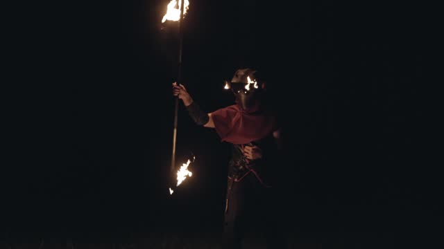 Man in a Dr. Plague mask spinning a scythe that is set on fire