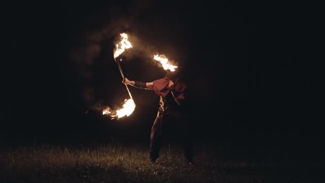 Man in a Dr. Plague mask spinning a scythe that is set on fire