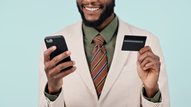Happy businessman, hands and credit card with phone in online shopping, banking or payment against a studio background. Closeup of black man with debit and mobile smartphone for ecommerce or bank app