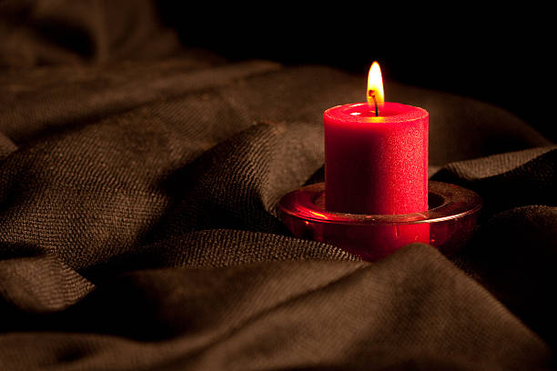 istock Flame Burning Red Candle on Black Rumpled Cloth 174636401