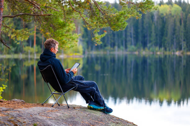 istock A man reads an e-book on the shore of a lake. 1746369913