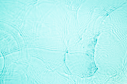 Close-up, directly above on turquoise transparent waving water texture with copy space.