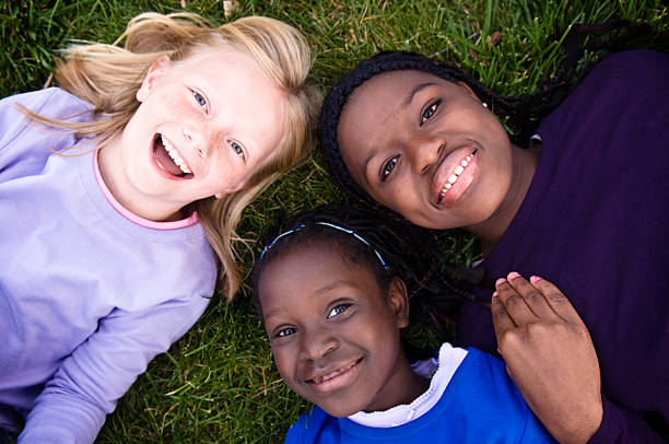 Three Happy Girls Smiling and Lying in the Grass