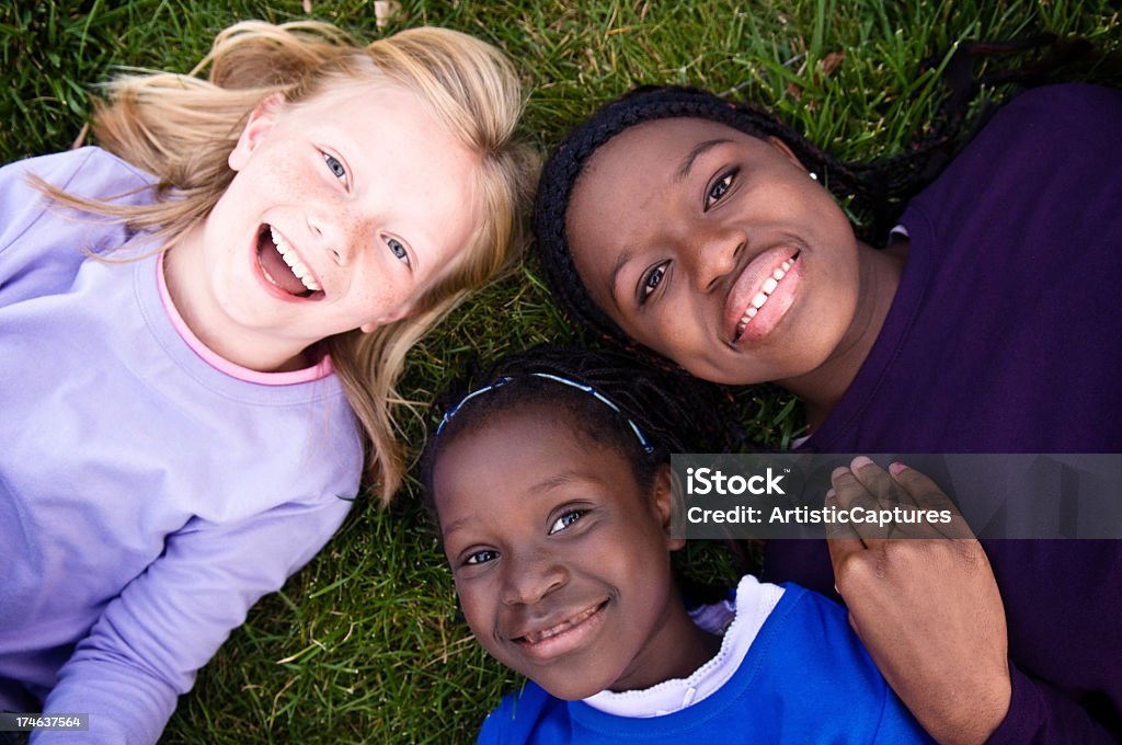 Trzy szczęśliwy dziewczynki uśmiech i leżeć na trawie - Zbiór zdjęć royalty-free (Blond włosy)