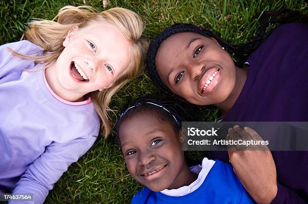 Três Felizes Meninas Sorridente E Deitada Na Relva - Fotografias de stock e mais imagens de Cabelo Louro - Cabelo Louro, De aparência caucasiana, Rir