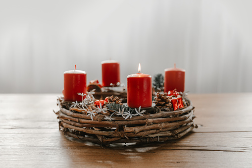 Advent wreath with first candle lit on advent sunday. Traditional diy christmas decoration.