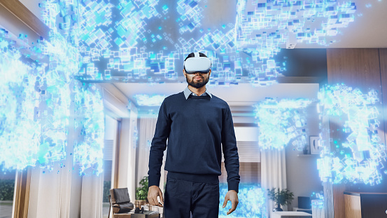 Young Indian Man Wearing a Virtual Reality Headset at Home. He Enters Digital Internet Universe, 3D Particles Transforming The Background. Next Generation Immersive Social Media Online Metaverse.