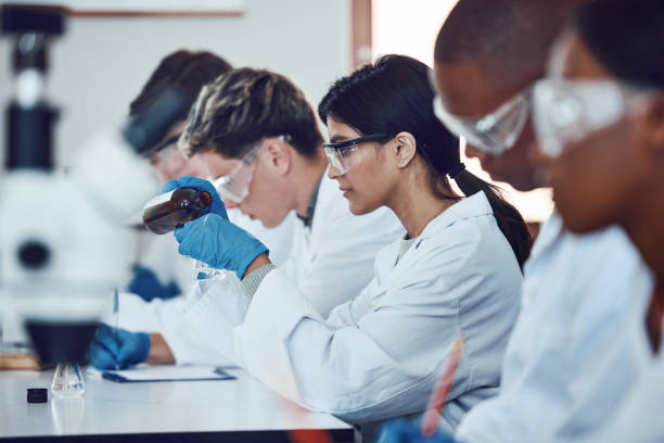 istock Diversity, scientist and people in science exam, test or group project in experiment or assignment at laboratory. PHD students in scientific research, chemical or forensics with safety uniform in lab 1746392641