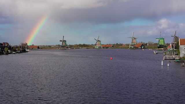 Historical dutch windmills in Zaanse Schans with beautiful rainbow in the sky