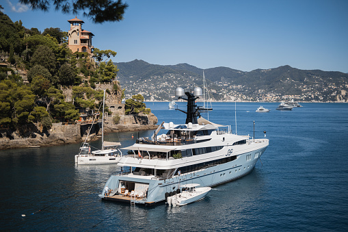 Portofino, Italy - September 25, 2023: White yacht against the backdrop of azure sea water - beautiful Mediterranean resort locations