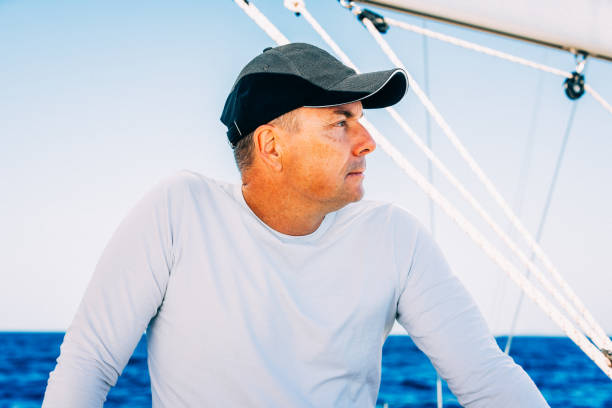Crew member enjoying sailing on sailboat standing at sailboat's entrance.