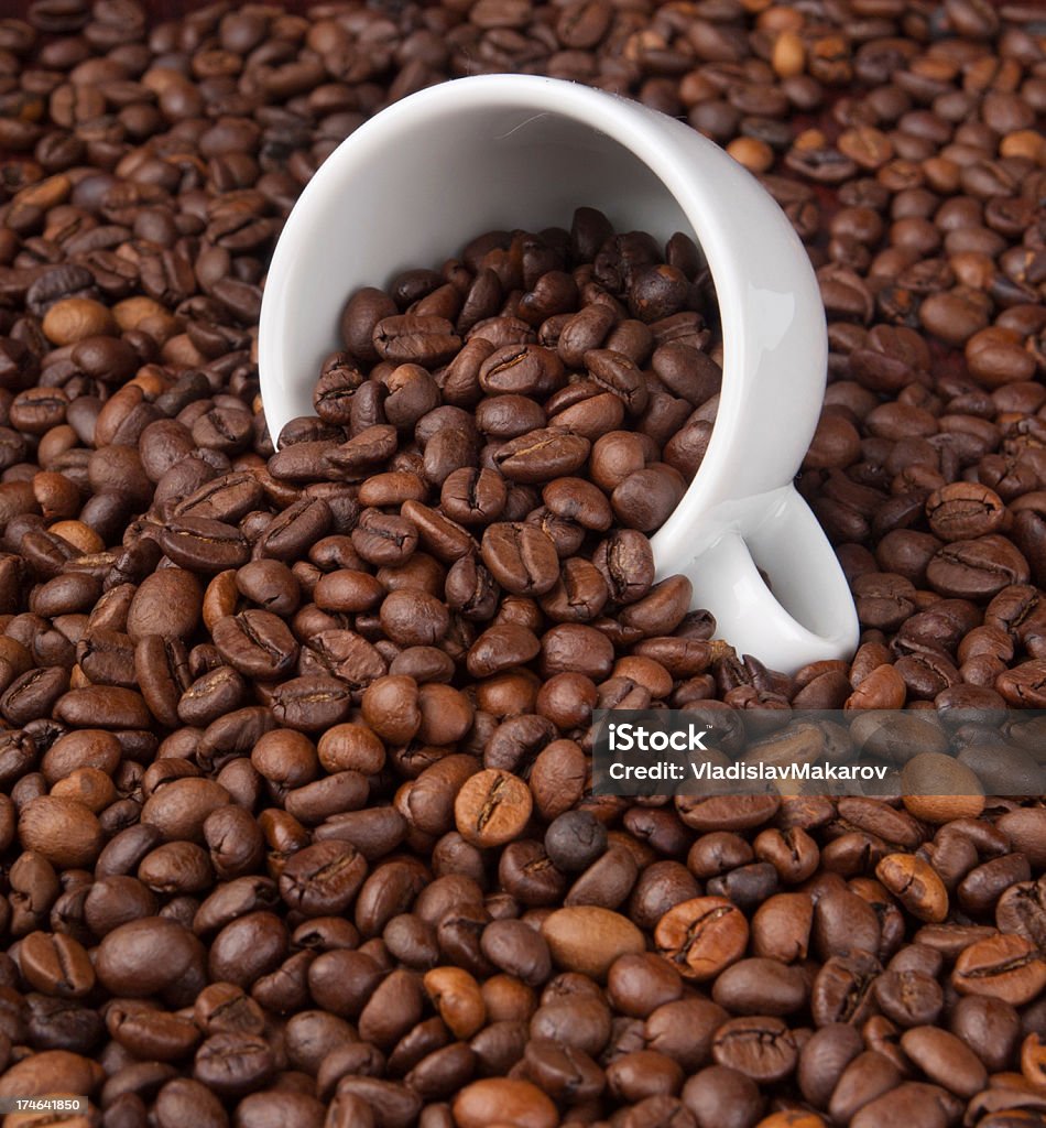 white cup with coffee beans A white cup with coffee beans on coffe background Brown Stock Photo