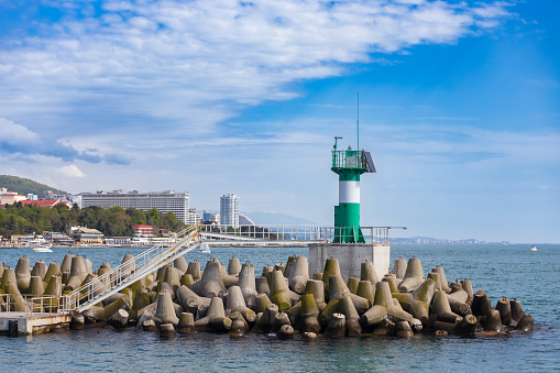 Sochi, Russia - April 19, 2023: modern lighthouse in the commercial port installed on concrete coastal fortifications or tetrapods. View from the sea