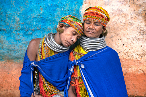Two women dressed in their traditional costumes from the Indian region of Odisha rest after working in the field