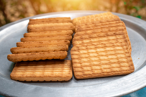Brown Wheat biscuits in the steel plate with blury background. Tea Biscuit morning breakfast