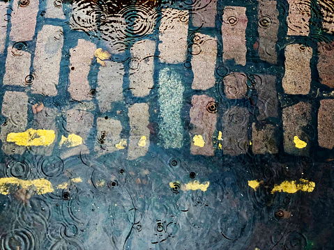 Raindrops in a puddle on a cobbled street in Norwich